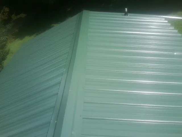 New green metal panels meeting at the ridge of a roof — Flat Roof Repair work by our crew in Sunnyvale