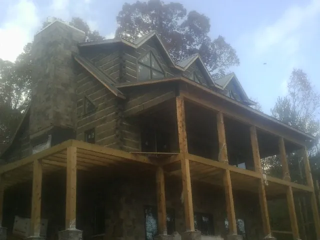 Stone chimney and dormers on a large log home with a timber porch in Sunnyvale