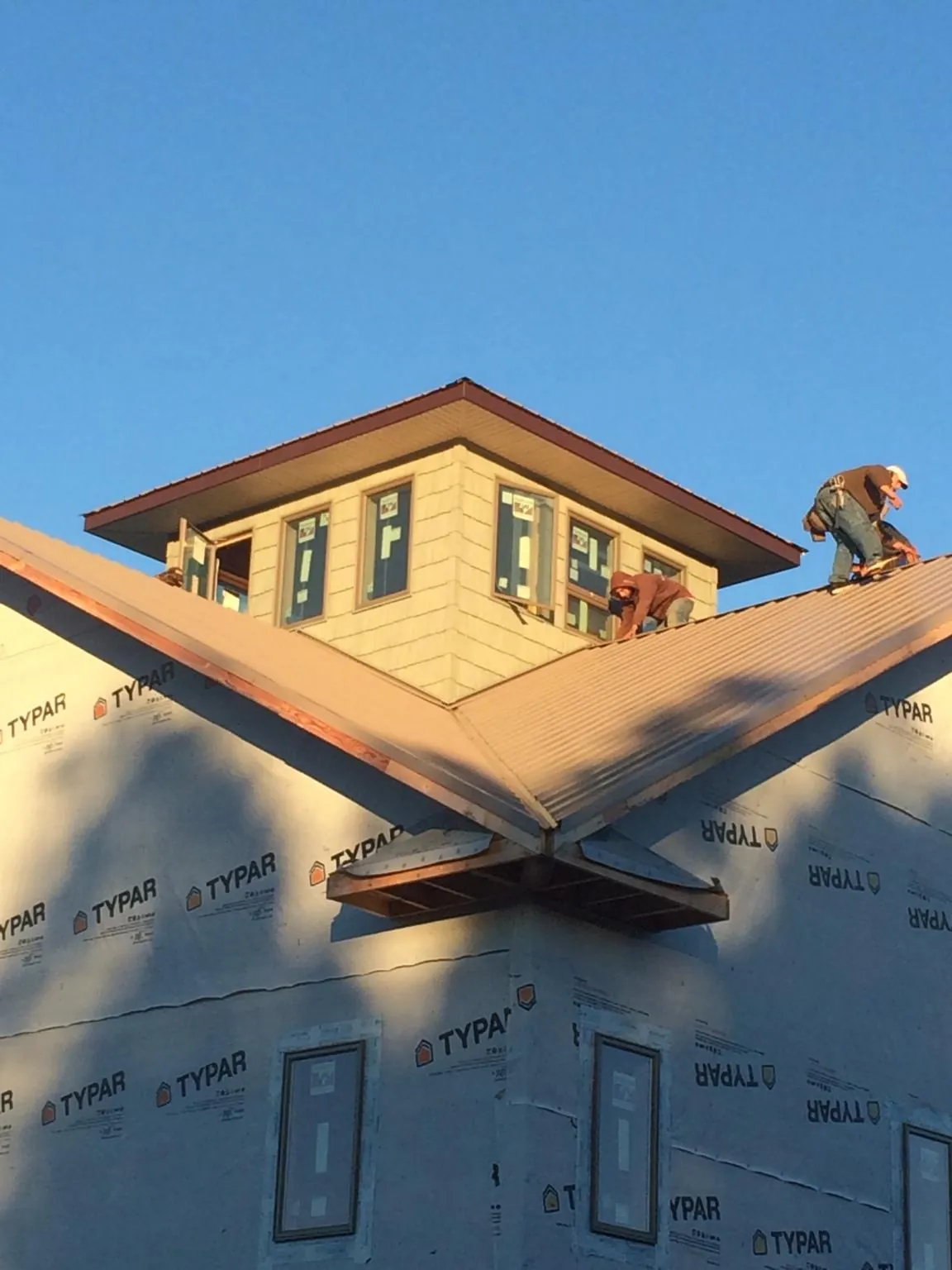Roofers working around a rooftop cupola on a new metal roof at sunset — Roof Waterproofing in Sunnyvale by Roofing Brothers